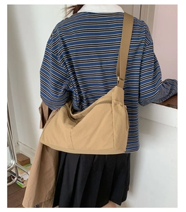 Close-up of khaki nylon dumpling bag showing the wide adjustable strap and side zipper pocket