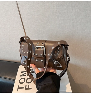 Detail view of dark brown punk baguette bag with silver studs and metal buckle decoration