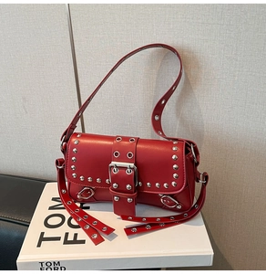 Detailed macro view of red matte leather baguette bag with silver studs and metal buckle