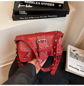 Close-up of red leather Y2K punk shoulder bag featuring silver rivets and belt buckle