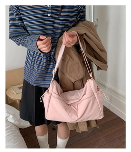 Detail of light pink nylon dumpling bag with adjustable strap and drawstring side pocket