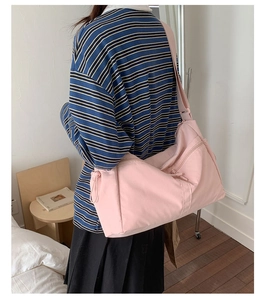Detail view of pink nylon crescent bag featuring double front zippers and adjustable strap