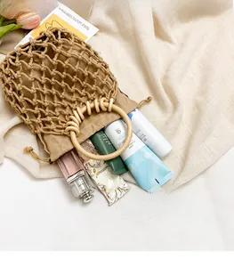 Detail view of woven mesh tote with inner drawstring bag and circular wooden handle