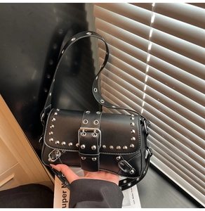 Detail of black leather punk baguette bag featuring silver rivets and wide buckle strap