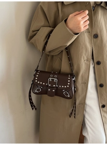 Detail shot of vintage dark brown baguette bag with silver studs on khaki trench coat