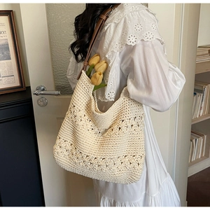 Detail of crochet floral pattern on a beige woven tote bag with brown leather strap