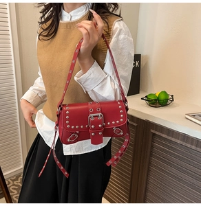 Detailed view of red leather shoulder bag with silver rivets and punk style tassels