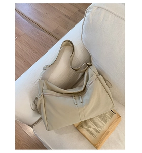 Detail of beige nylon crossbody bag with dual zipper pockets and adjustable wide strap