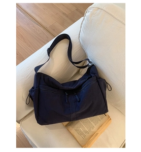 Detail of dark blue nylon hobo bag showing multiple zipper pockets and side drawstrings