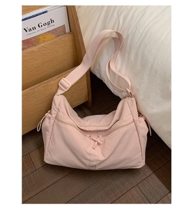 Detail of light pink nylon dumpling bag showing adjustable strap and drawstring side detail