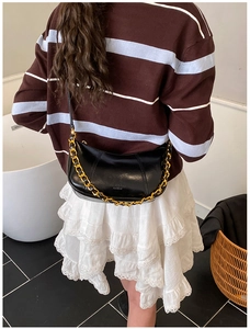 Detail der schwarzen glänzenden Hobo-Tasche mit Goldkette und Markenprägung