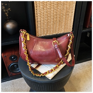 Detailansicht der burgunderroten Halbmond-Tasche mit glänzendem Leder und goldener Kette