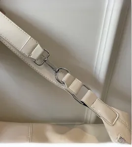 Close-up of ivory leather shoulder strap with polished silver metal hook and D-ring