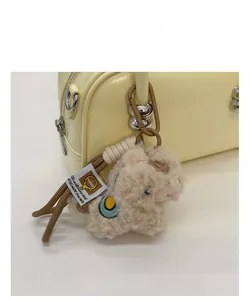 Nahaufnahme eines flauschigen Alpaka-Anhängers mit Stickerei an einer gelben Handtasche