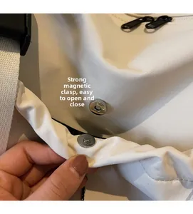 Detailaufnahme der starken Magnetschnalle an der weißen Canvas-Reisetasche mit Metallbeschlägen