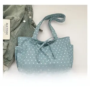 Detail of light blue canvas tote bag with white star pattern and handmade metal tag