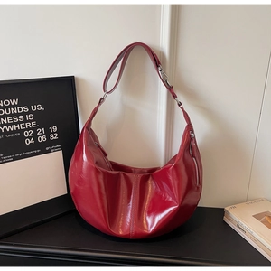 Detail of red glossy leather hobo bag with vertical stitching and silver side zipper