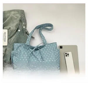 Detail view of a light blue canvas tote bag featuring star prints and a bow decoration