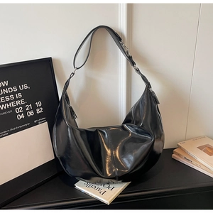 Detail of black glossy hobo bag with sleek mirror finish and silver metal zipper