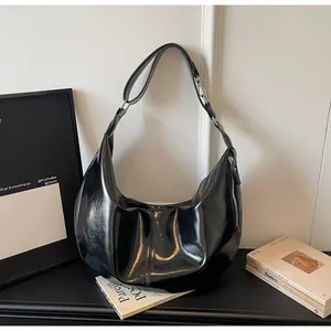 Detailed view of large black shiny patent leather hobo bag with silver zipper detail