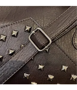 Detail of dark brown lychee texture leather with silver pyramid studs and metal buckle