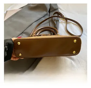Vue détaillée du fond du sac bowling avec pieds en métal doré et texture en cuir premium