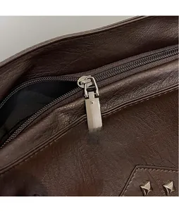 Macro shot of dark brown lychee grain PU leather with silver hardware and square rivets