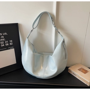 Detail view of light blue glossy faux leather crossbody bag with side zipper and strap