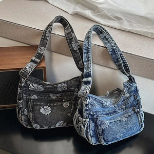 Close-up of blue and grey denim crossbody bags with daisy embroidery and multiple pockets