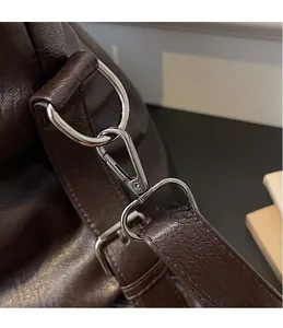 Close-up of durable silver metal swivel hook on dark brown pebbled leather shoulder bag