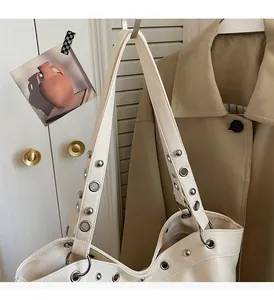 Detail of silver rivets and metal eyelets on a cream-colored leather tote bag