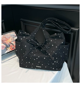 Macro shot of black canvas tote bag with star prints, bow tie detail and side pocket