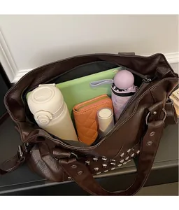 Top view of spacious brown rivet tote bag interior showing water bottle and tablet