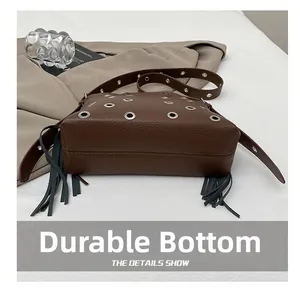 Dettaglio borsa in pelle marrone con occhielli in metallo argento e nappe nere