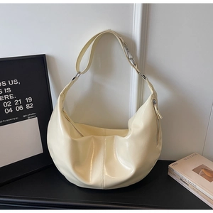 Detailed view of glossy cream hobo bag showing wide strap and metallic zipper textures