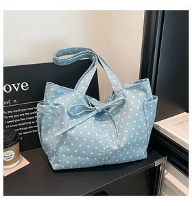 Detail of light blue canvas tote bag featuring star pattern and large bow decoration
