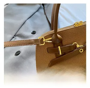 Détail d'un sac à main en cuir marron texturé avec garnitures dorées et coutures fines