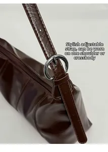 Detail of adjustable silver buckle strap on dark brown glossy leather shoulder bag