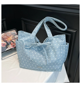 Detail of light blue star print tote bag with bow accent and handmade metal plate