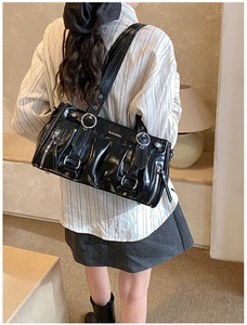 Détail d'un sac cabas noir plissé brillant avec anneaux argentés et boucles métalliques