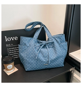 Detailed view of blue denim tote bag with white star pattern and side pocket details