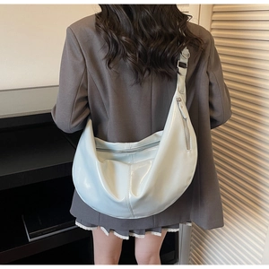 Detail of light blue patent leather hobo bag with glossy finish and silver hardware