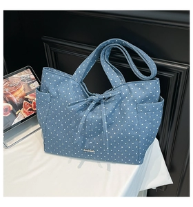 Detail of blue denim tote bag with star print, handmade plate and bow decoration