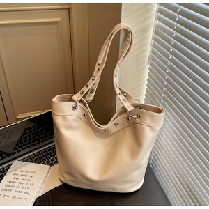Detail of beige large tote bag with silver metal eyelets and long shoulder straps