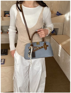 Détail du sac à main texturé bleu clair avec lanières en cuir marron et zip doré