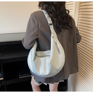 Detail of light blue glossy crescent shoulder bag showing its texture and large capacity