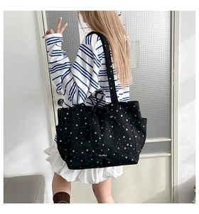 Black canvas tote bag with white stars, bow detail and spacious design for daily commute