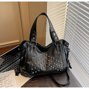 Detail of silver pyramid studs on black pebble leather tote bag with sturdy handles