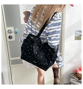 Close-up of black canvas tote bag featuring white star prints and handmade embroidery detail