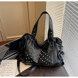 Close-up of black tote bag with silver square rivets and adjustable strap detail